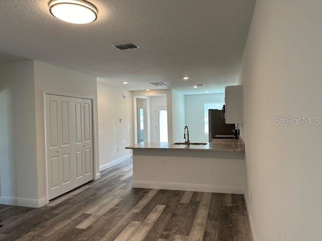 A kitchen with a breakfast bar and wood-look flooring opens to a living area — 542 KILIMANJARO, KISSIMMEE, FL