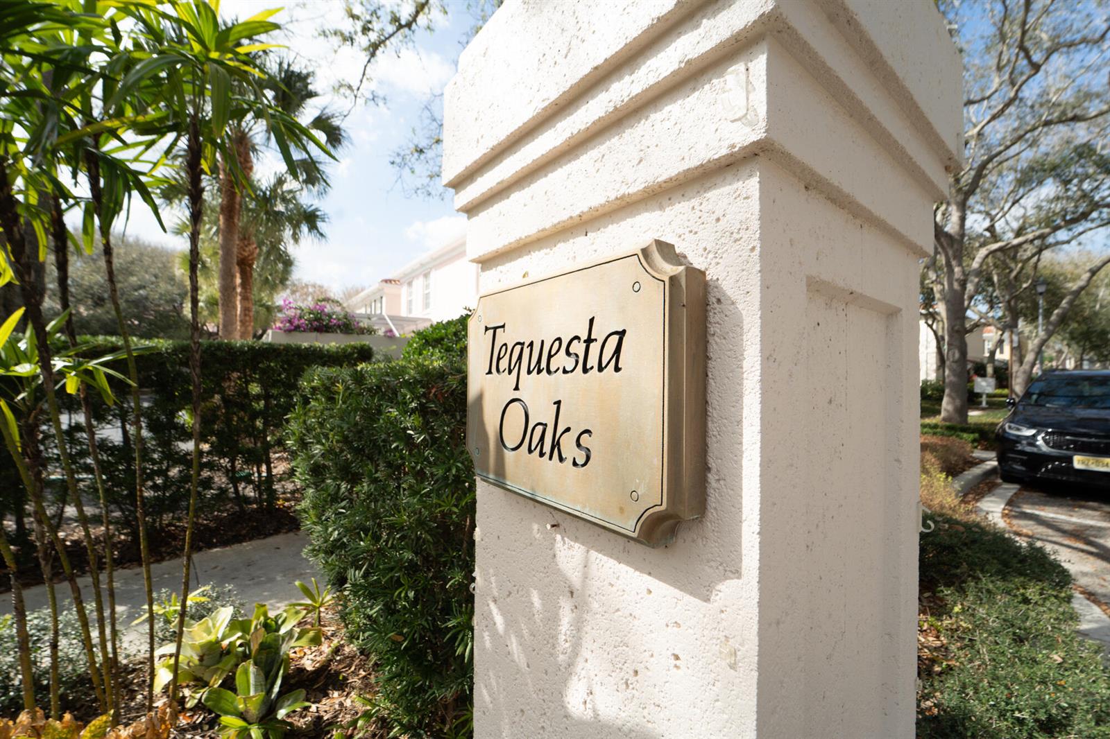 A stone pillar displays a sign for Tequesta Oaks near a palm tree and driveway — 3 Oakland Court, Tequesta FL 33469, TEQUESTA, FL