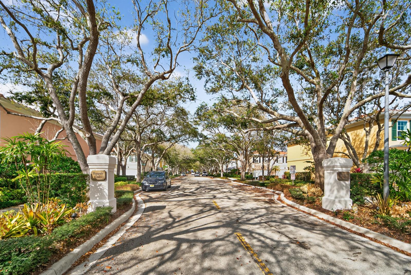 A tree-lined street leads into a residential community with two stone pillars at the entrance — 3 Oakland Court, Tequesta FL 33469, TEQUESTA, FL