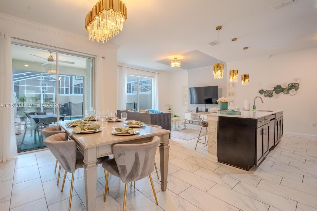An open-concept dining and kitchen area features a large island, pendant lighting, and tile flooring — 962 splash Shot  Pl, Kissimmee FL 33896, KISSIMMEE, FL