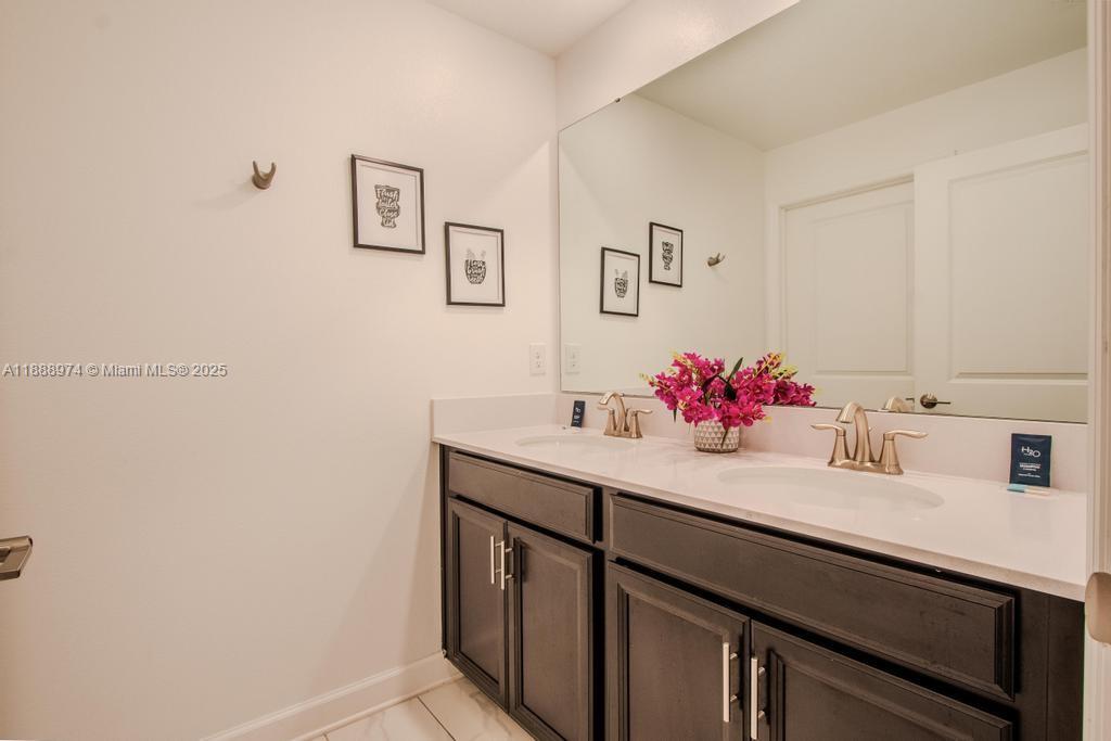 A bathroom features a double vanity with dark cabinets, white countertops, and a large mirror — 962 splash Shot  Pl, Kissimmee FL 33896, KISSIMMEE, FL