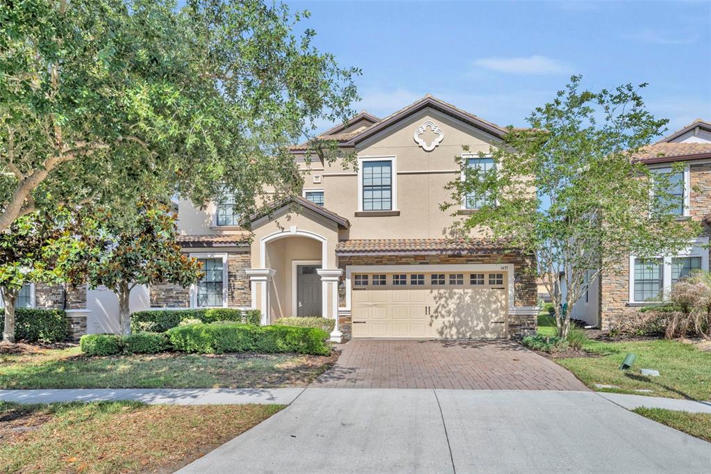 A two-story suburban home features a beige stucco facade, stone accents, and a two-car garage — 1435 ROLLING FAIRWAY DRIVE, DAVENPORT, FL