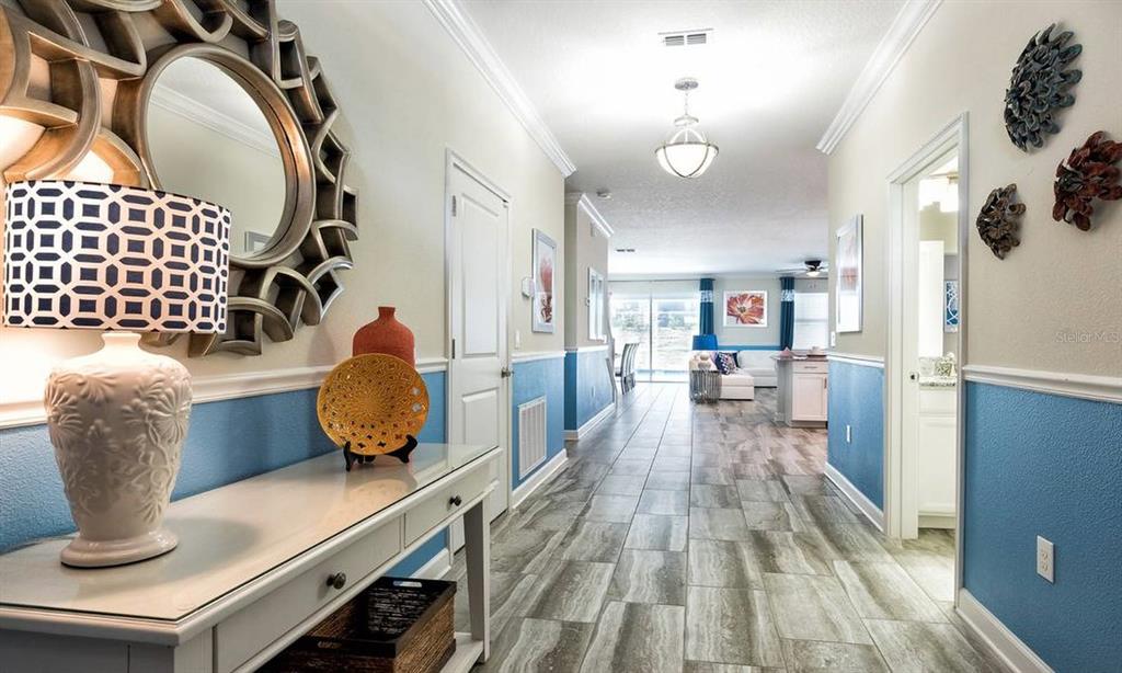 A hallway with blue wainscoting, tile flooring, and a console table leads to a living area — 9095 HAZARD STREET, DAVENPORT, FL