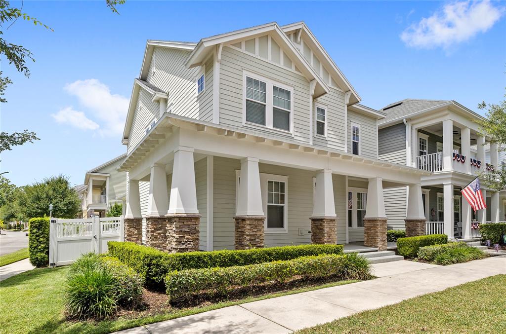 A two-story house with light green siding, a front porch, and stone-based columns — 1569 RESOLUTE STREET, KISSIMMEE, FL