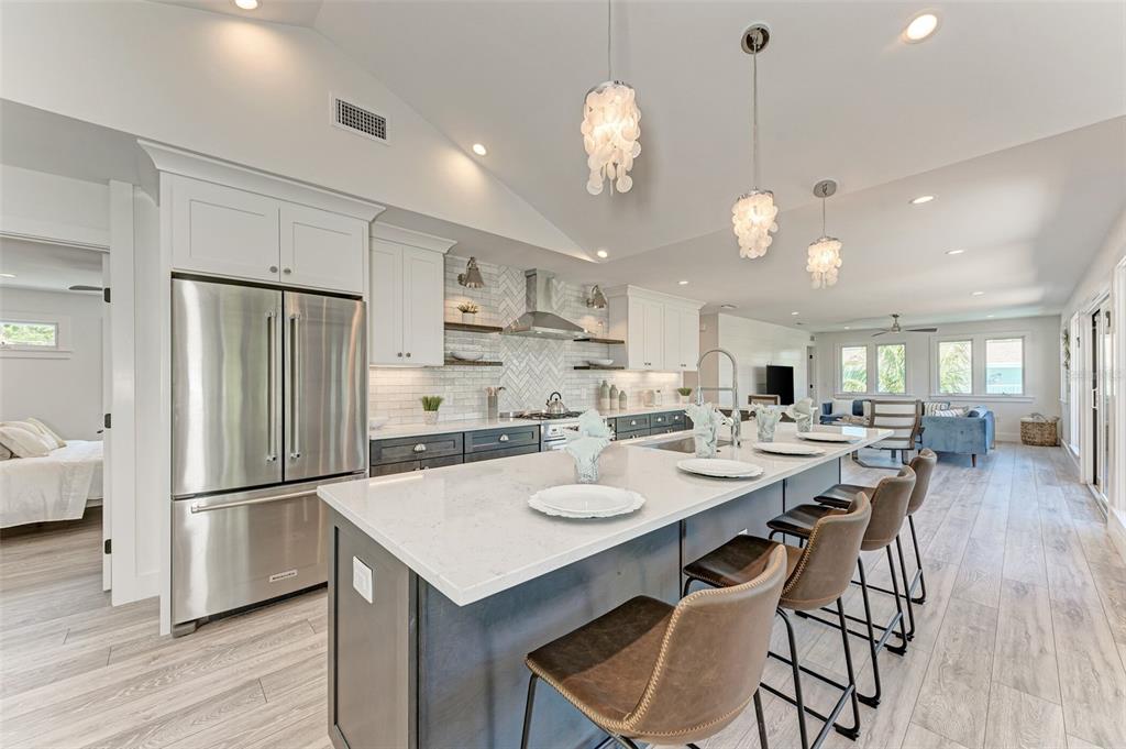 A modern kitchen features a large island with bar seating, white cabinets, and stainless appliances — 256 GLADIOLUS STREET, ANNA MARIA, FL