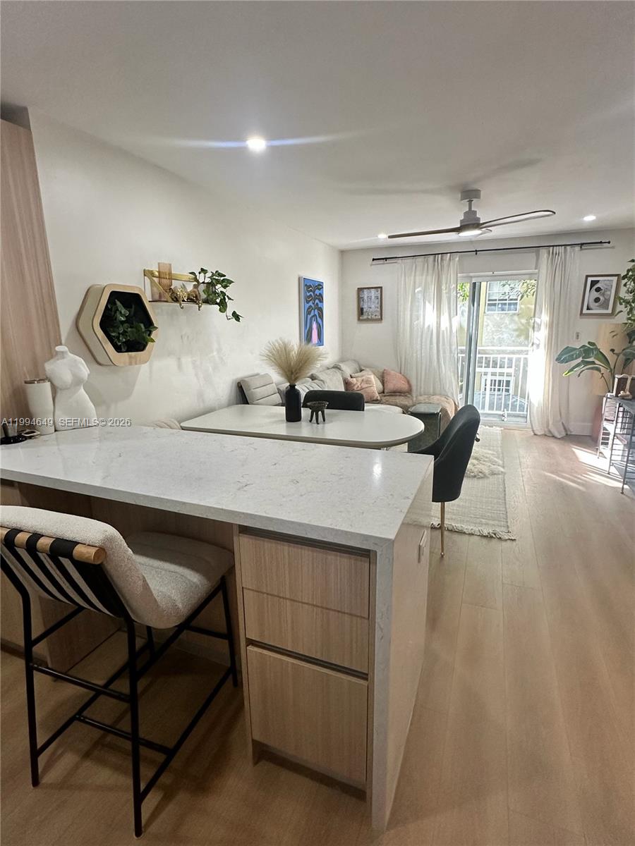 A kitchen island with white countertops overlooks a dining area and a living room — 1519 Drexel Ave # 200, Miami Beach FL 33139, MIAMI BEACH, FL