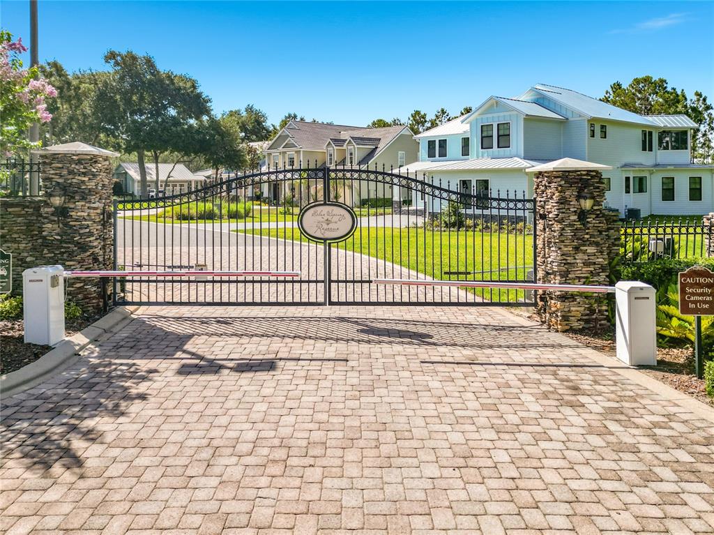 A gated entrance with stone pillars leads to a residential neighborhood with houses — 466 LONG AND WINDING ROAD, HOWEY IN THE HILLS, FL