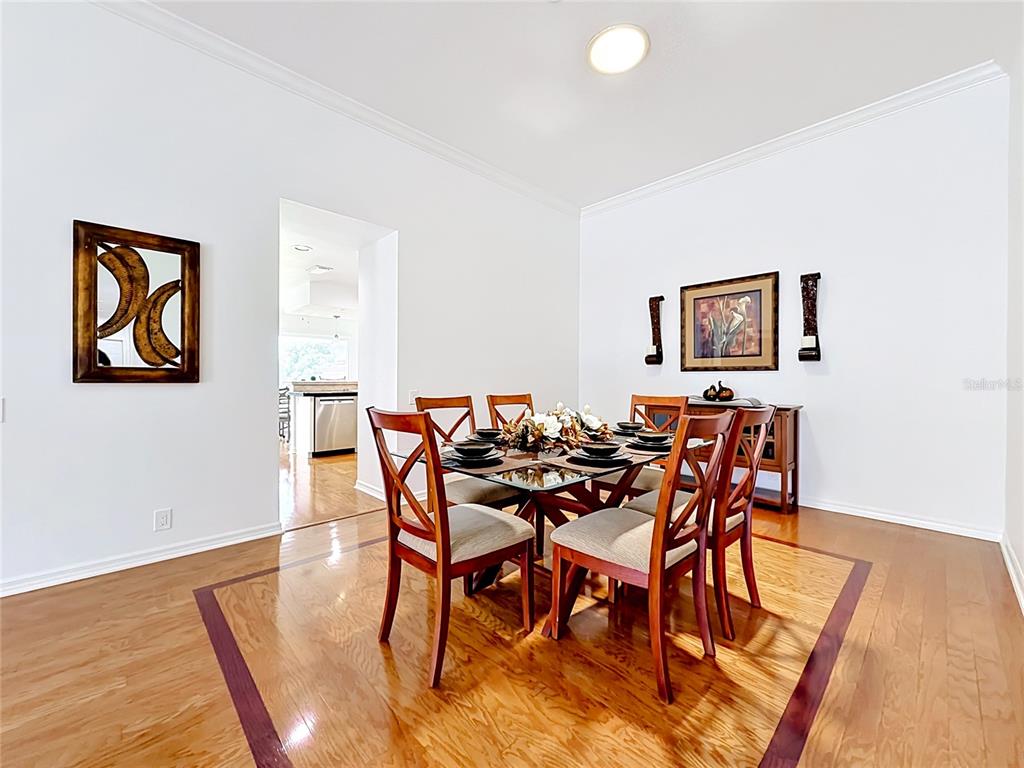 A dining room features a glass-topped table, wooden chairs, and hardwood floors with inlays — 6042 TOPSAIL ROAD, LADY LAKE, FL