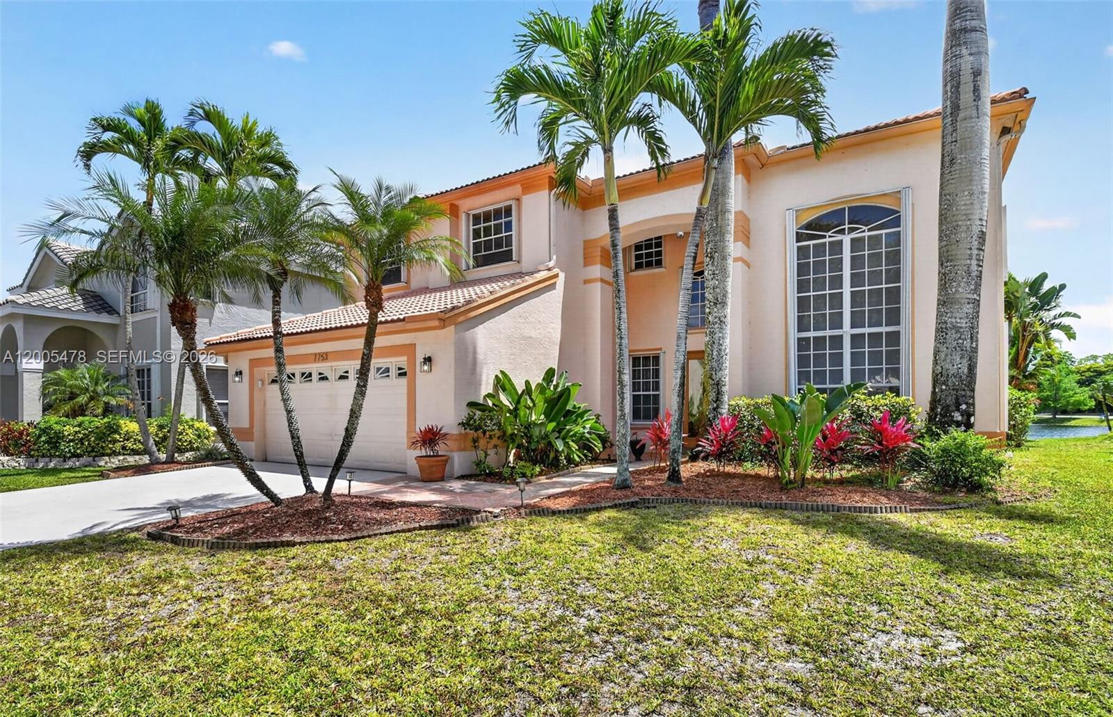 A two-story suburban house with a beige stucco exterior, a tile roof, and palm trees — 7753 Cedar Hurst Ct, Lake Worth FL 33467, LAKE WORTH, FL