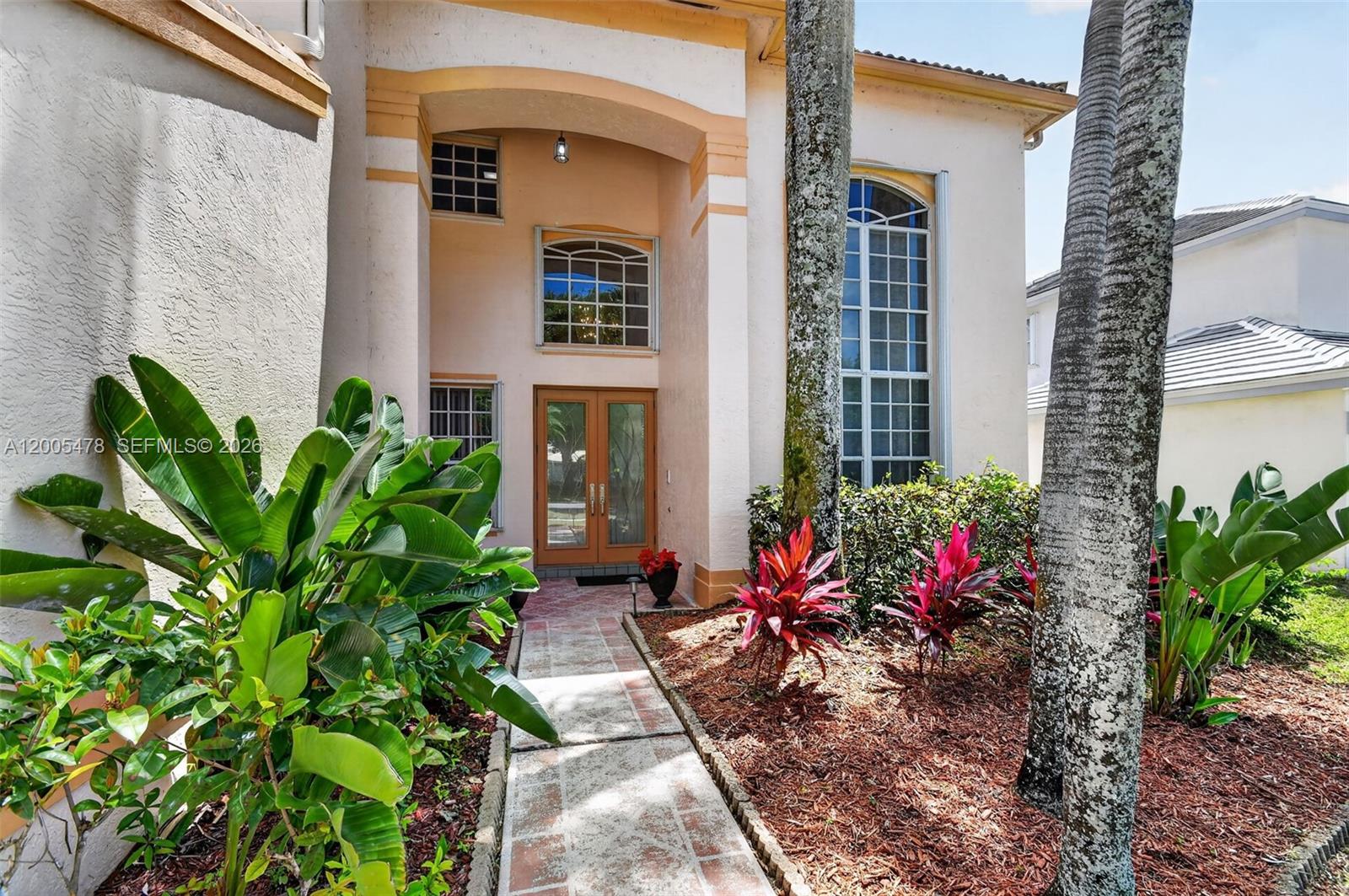 The exterior of a two-story house features a paved walkway leading to a double-door entrance — 7753 Cedar Hurst Ct, Lake Worth FL 33467, LAKE WORTH, FL