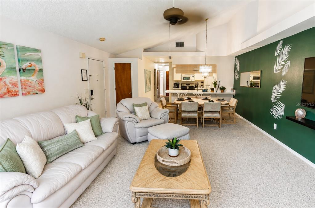 A living room with a white sofa, armchair, coffee table, and a green accent wall — 2440 SWEETWATER CLUB CIRCLE UNIT 40, KISSIMMEE, FL