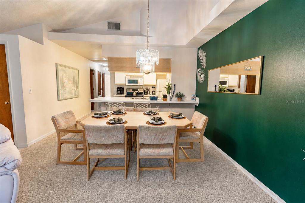 A dining area with a wooden table, six chairs, and a green accent wall — 2440 SWEETWATER CLUB CIRCLE UNIT 40, KISSIMMEE, FL