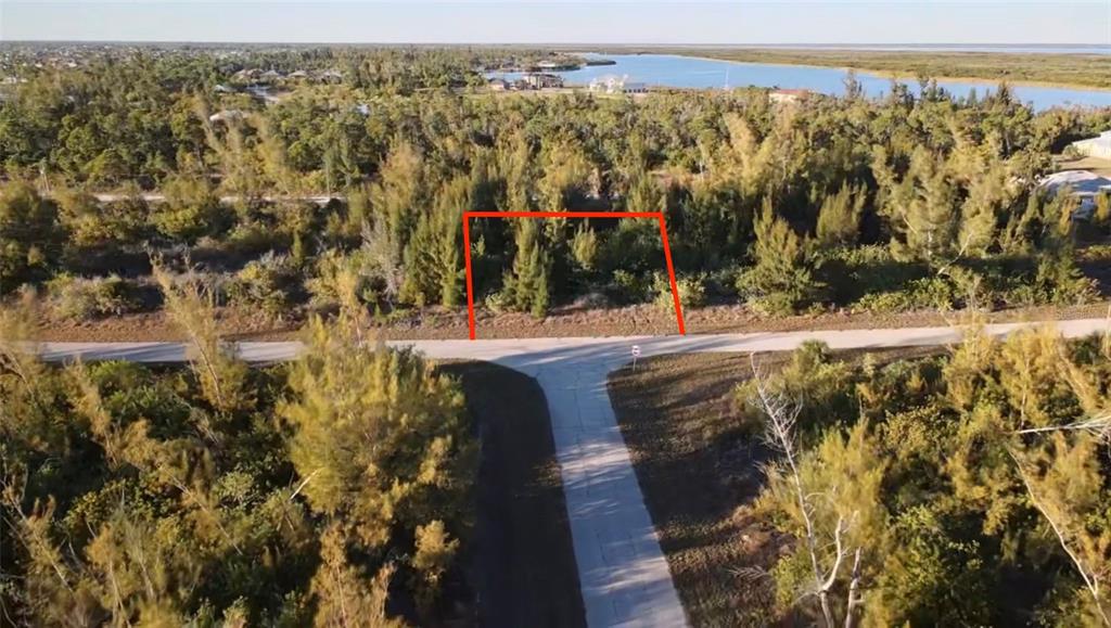An aerial view shows a vacant, wooded lot outlined in red along a paved road — 10549 ABELLO ROAD, PORT CHARLOTTE, FL