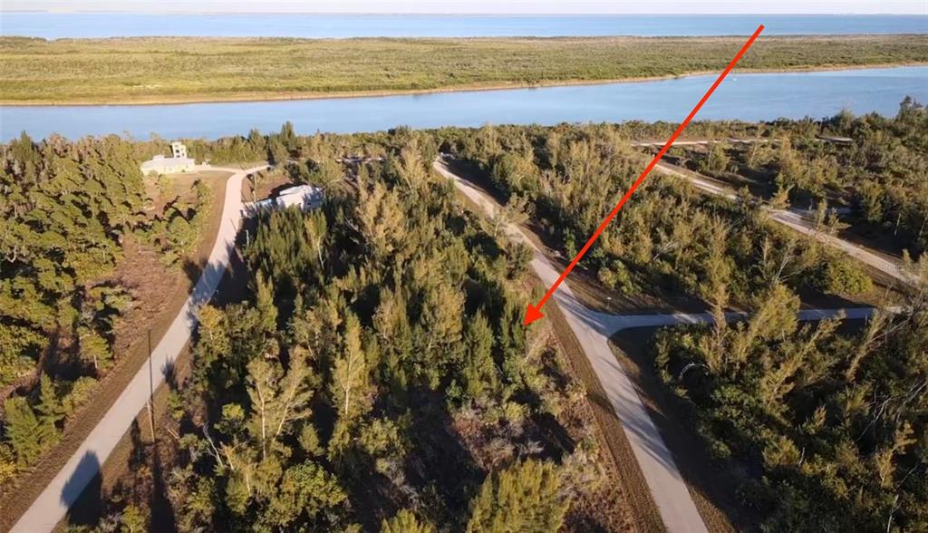 An aerial view shows a wooded, undeveloped lot situated near a river and coastal waters — 10549 ABELLO ROAD, PORT CHARLOTTE, FL