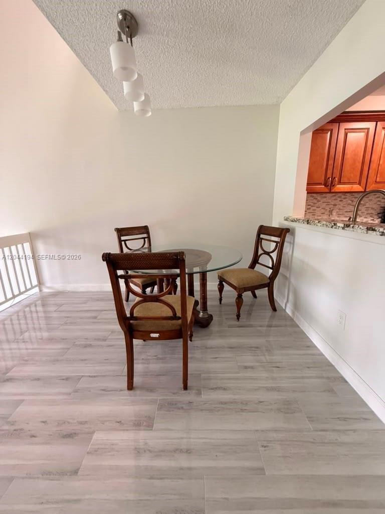 A dining area features a glass-topped table, three wooden chairs, and light-colored tile flooring — 4182 S Pine Island Rd, Davie FL 33328, DAVIE, FL