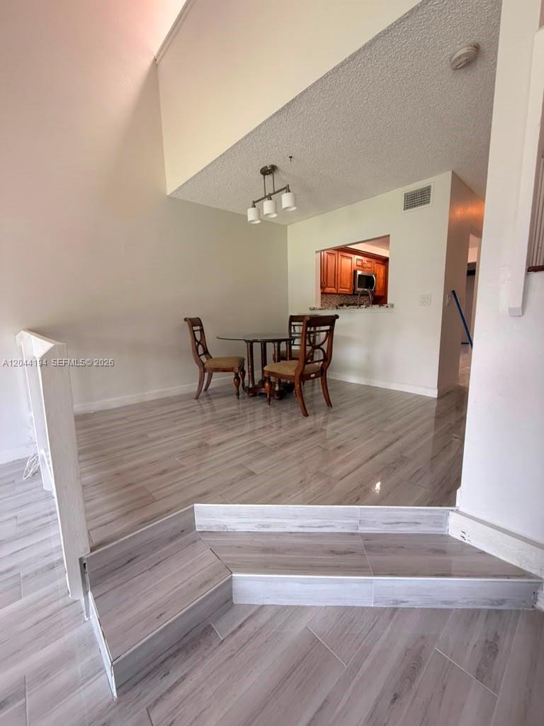 A dining area features light wood-look tile flooring, a glass table, and two chairs — 4182 S Pine Island Rd, Davie FL 33328, DAVIE, FL