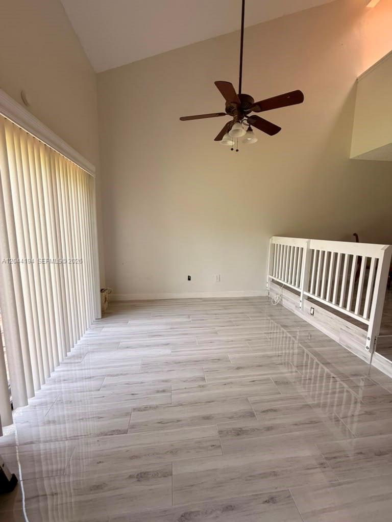A room with light wood-look tile flooring, a vaulted ceiling, and a white wooden railing — 4182 S Pine Island Rd, Davie FL 33328, DAVIE, FL