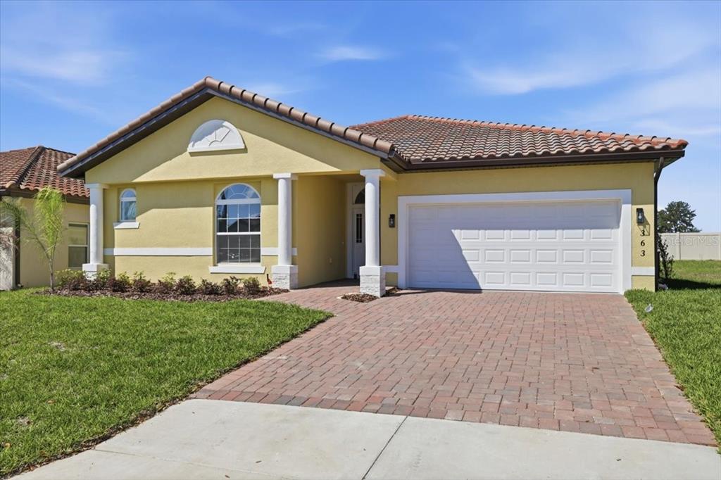 A single-story yellow house with a tile roof, two white columns, and a brick driveway — 363 VILLA SORRENTO CIRCLE, HAINES CITY, FL