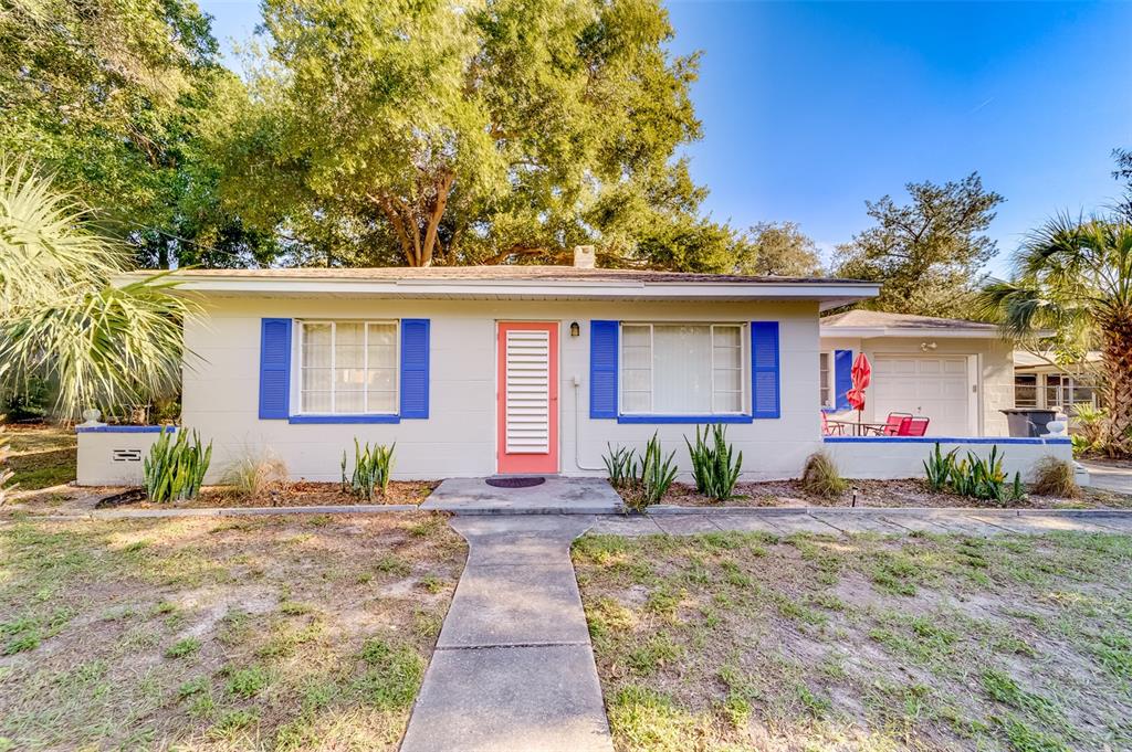 A single-story house with a coral door, blue shutters, and a concrete walkway — 10802 MOHAWK ROAD, ST PETERSBURG, FL