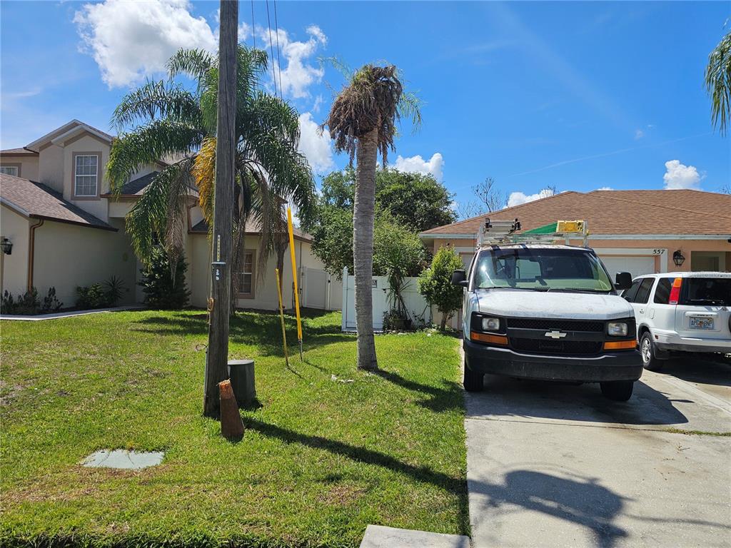 A white work van is parked in the driveway of a suburban house with palm trees — 557 EAGLE COURT, KISSIMMEE, FL