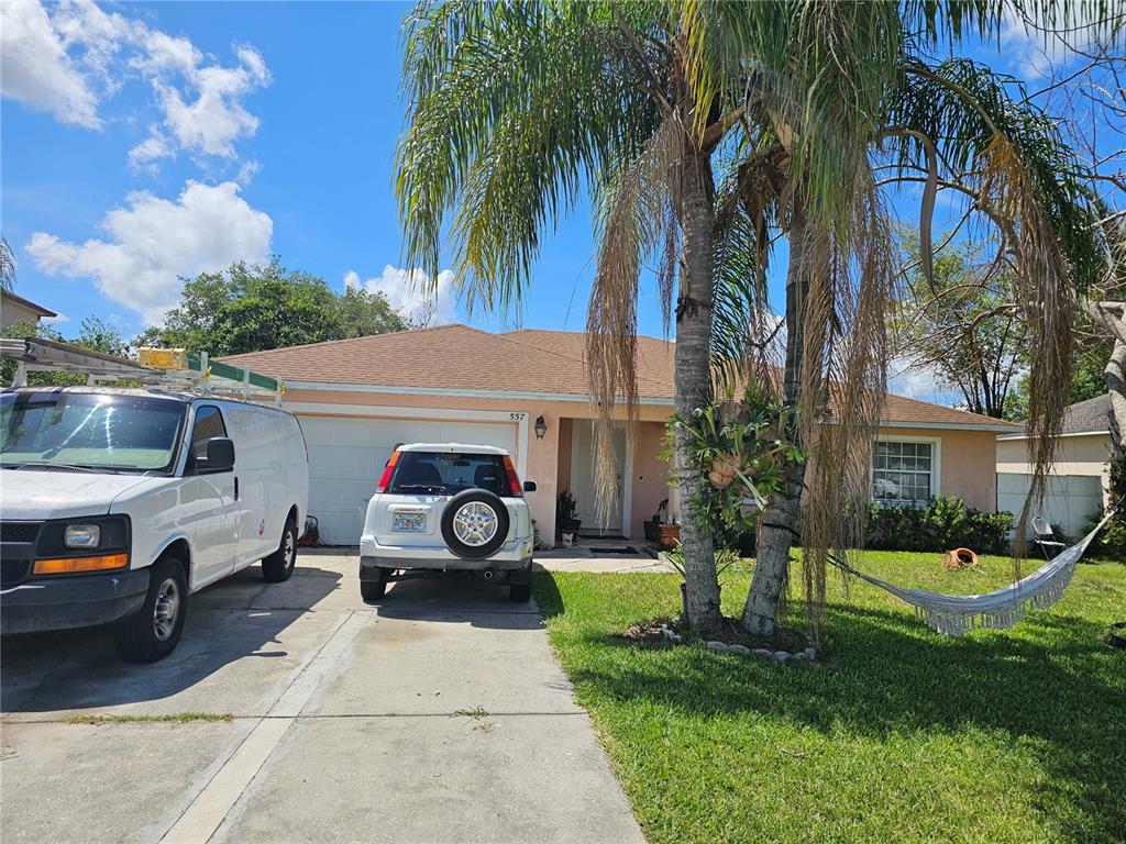 A single-story house with a peach exterior, a two-car garage, and palm trees in front — 557 EAGLE COURT, KISSIMMEE, FL