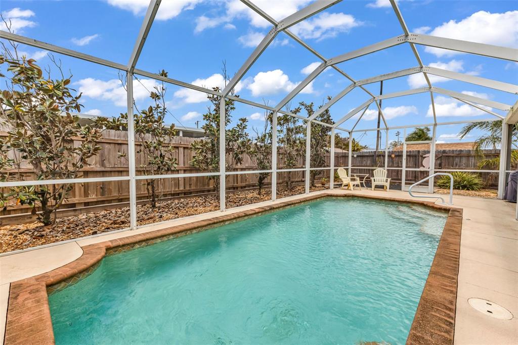A swimming pool is enclosed by a white metal screen cage in a backyard — 29180 CRAWFORD AVENUE, PUNTA GORDA, FL