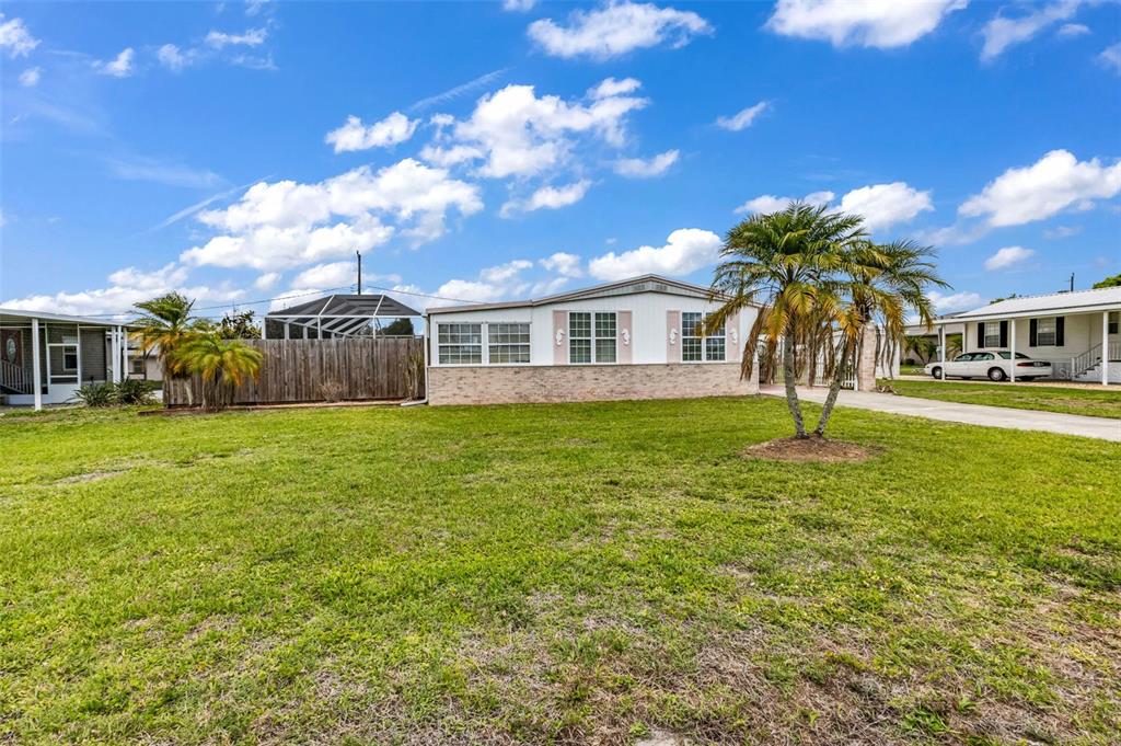 A single-story manufactured home with a brick facade sits on a large grassy lot — 29180 CRAWFORD AVENUE, PUNTA GORDA, FL