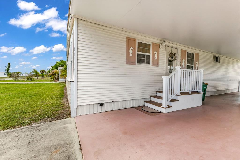 A white mobile home exterior features a covered carport, stairs, and light-colored siding — 29180 CRAWFORD AVENUE, PUNTA GORDA, FL