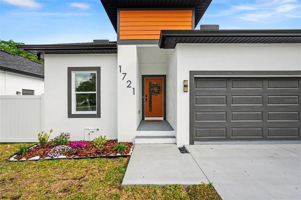 The exterior of a modern house features a white facade, orange accents, and a garage — 1719 W PERIO STREET, TAMPA, FL