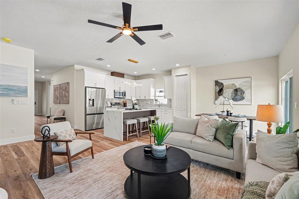 An open-concept living room and kitchen featuring a marble island, wood floors, and modern decor — 1719 W PERIO STREET, TAMPA, FL