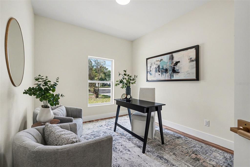 A home office features two gray armchairs, a black desk, and a large wall painting — 1719 W PERIO STREET, TAMPA, FL
