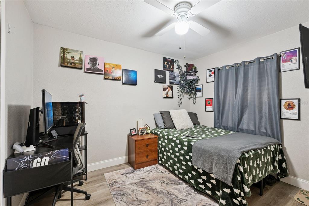 A bedroom features a desk, a twin bed with a green patterned quilt, and wall art — 1335 YVONNE STREET, APOPKA, FL