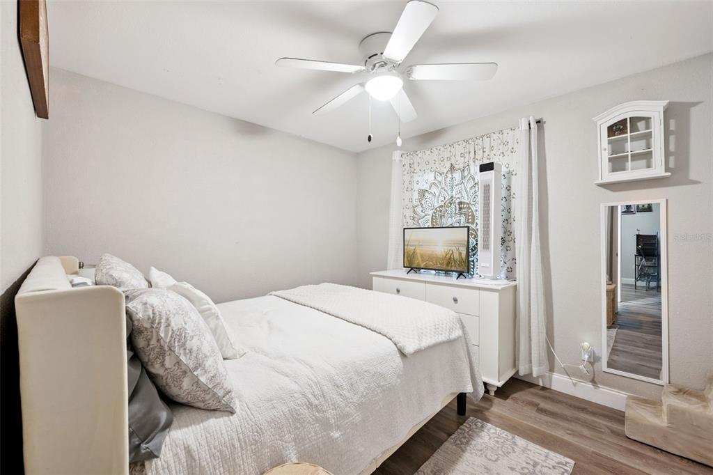 A bedroom features a white bed, a dresser with a television, and a wall mirror — 1335 YVONNE STREET, APOPKA, FL