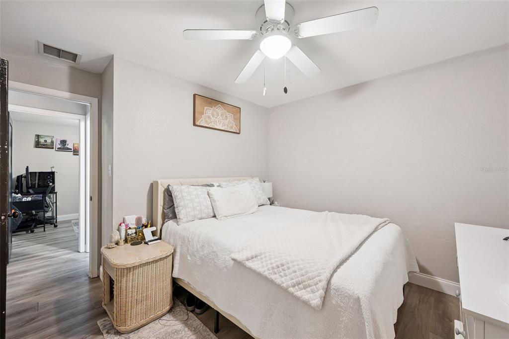 A bedroom features a bed with white bedding, a wicker nightstand, and a ceiling fan — 1335 YVONNE STREET, APOPKA, FL