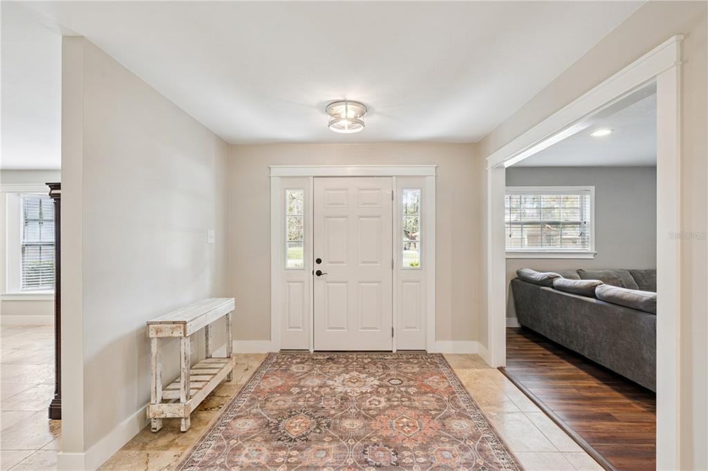An entryway features a white front door, a patterned rug, and a rustic console table — 14335 FRESNO DRIVE, ORLANDO, FL