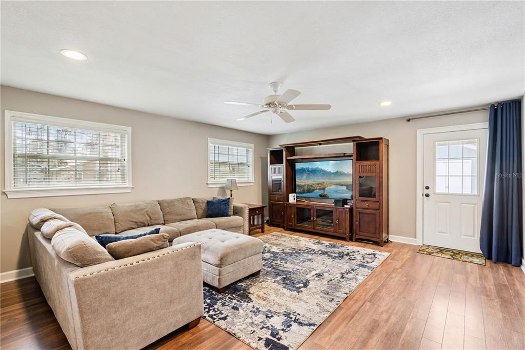 A living room features a sectional sofa, an area rug, and a wooden entertainment center — 14335 FRESNO DRIVE, ORLANDO, FL