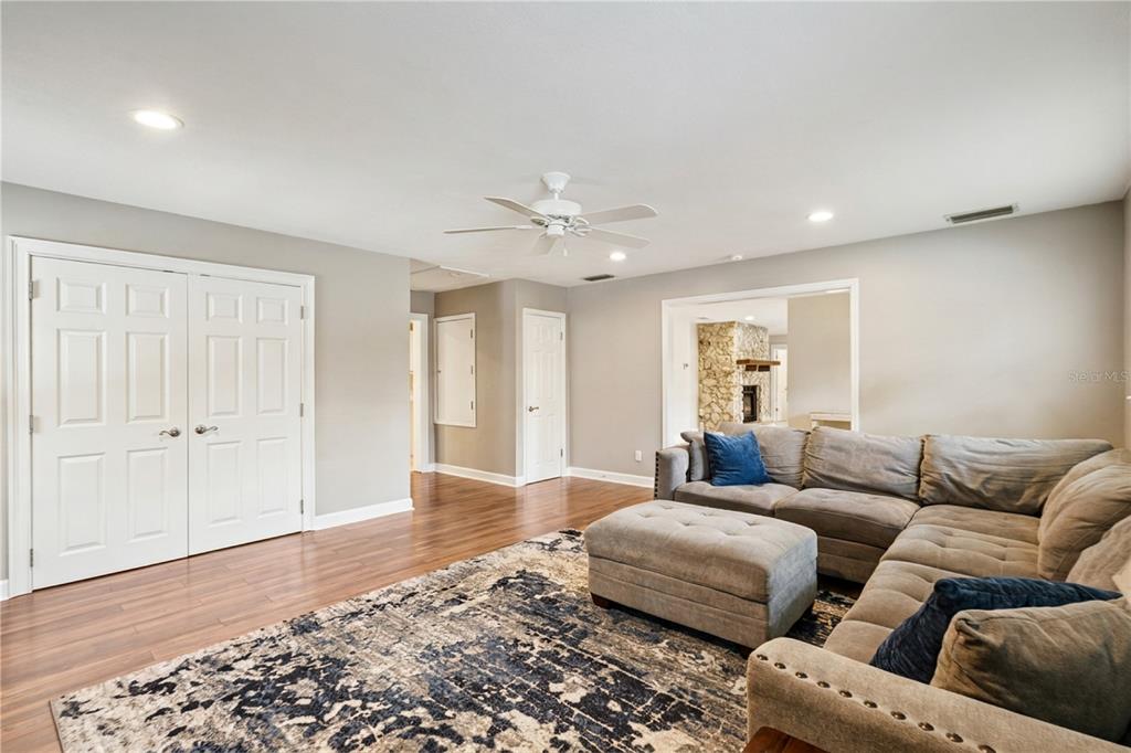 A living room features wood flooring, a sectional sofa, a ceiling fan, and white doors — 14335 FRESNO DRIVE, ORLANDO, FL
