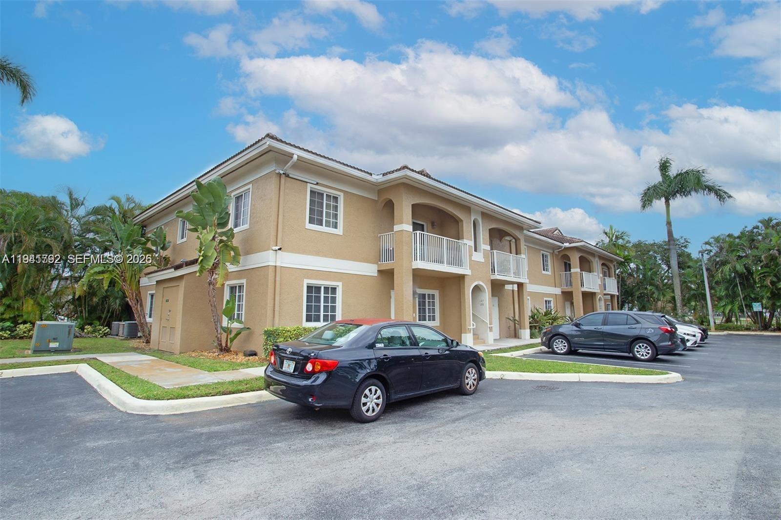 A two-story tan apartment building with a parking lot in the foreground — 911 Hillcrest Ct # 127, Hollywood FL 33021, HOLLYWOOD, FL