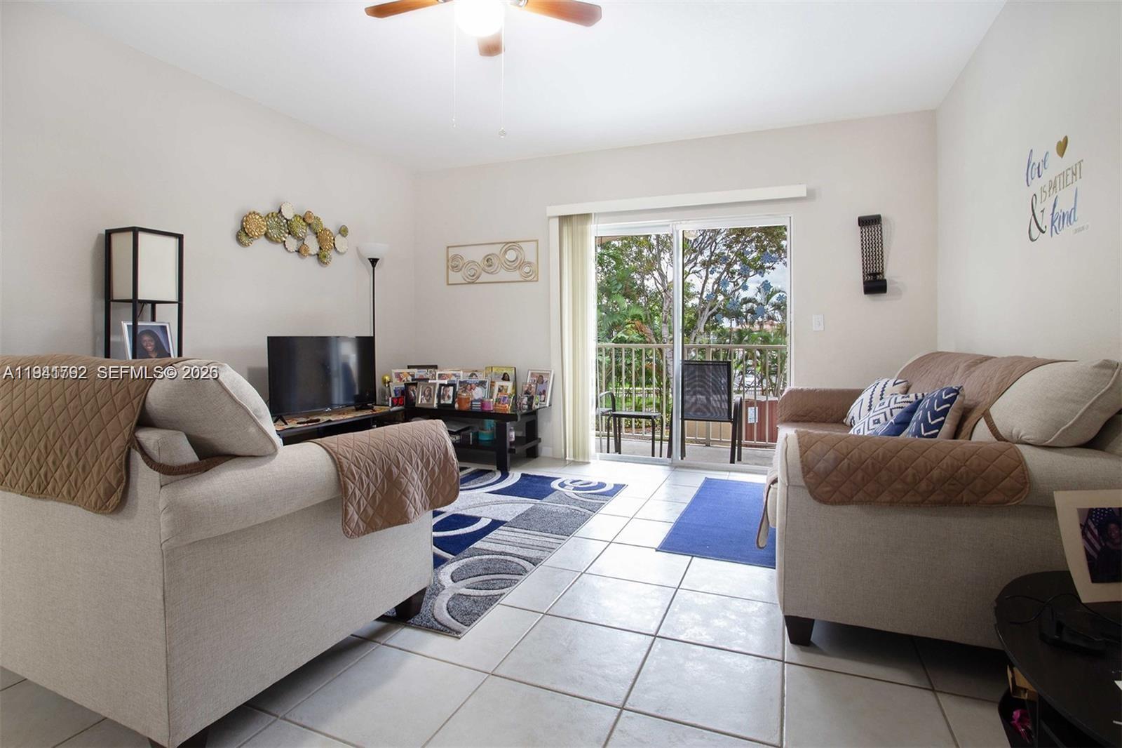 A living room features light-colored sofas, tile flooring, a patterned area rug, and a sliding door — 911 Hillcrest Ct # 127, Hollywood FL 33021, HOLLYWOOD, FL