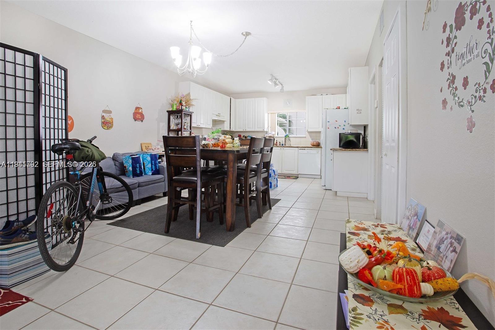 A dining area with a wooden table and chairs sits adjacent to a white kitchen — 911 Hillcrest Ct # 127, Hollywood FL 33021, HOLLYWOOD, FL