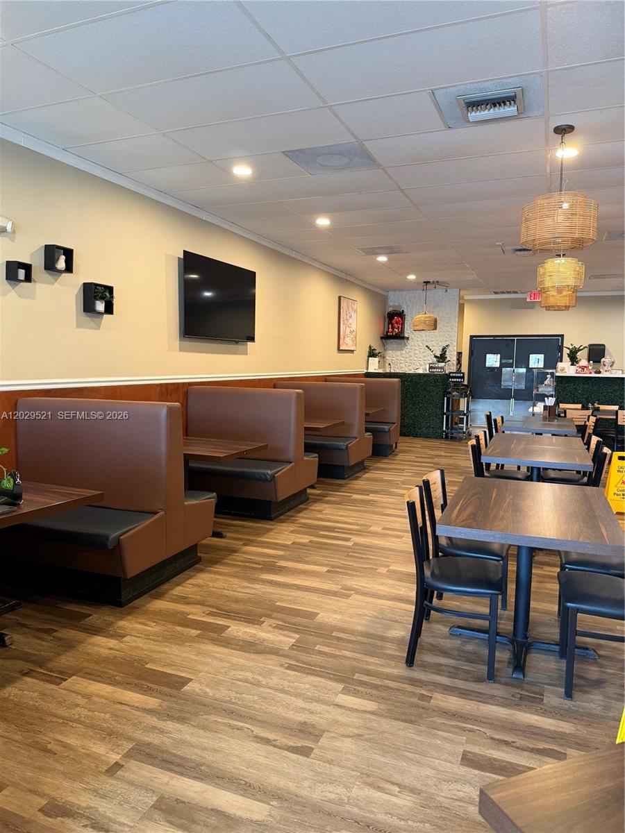 A restaurant interior features brown booth seating, wooden tables, and wood-look flooring — 7462 Royal Palm Blvd, Margate FL 33063, MARGATE, FL