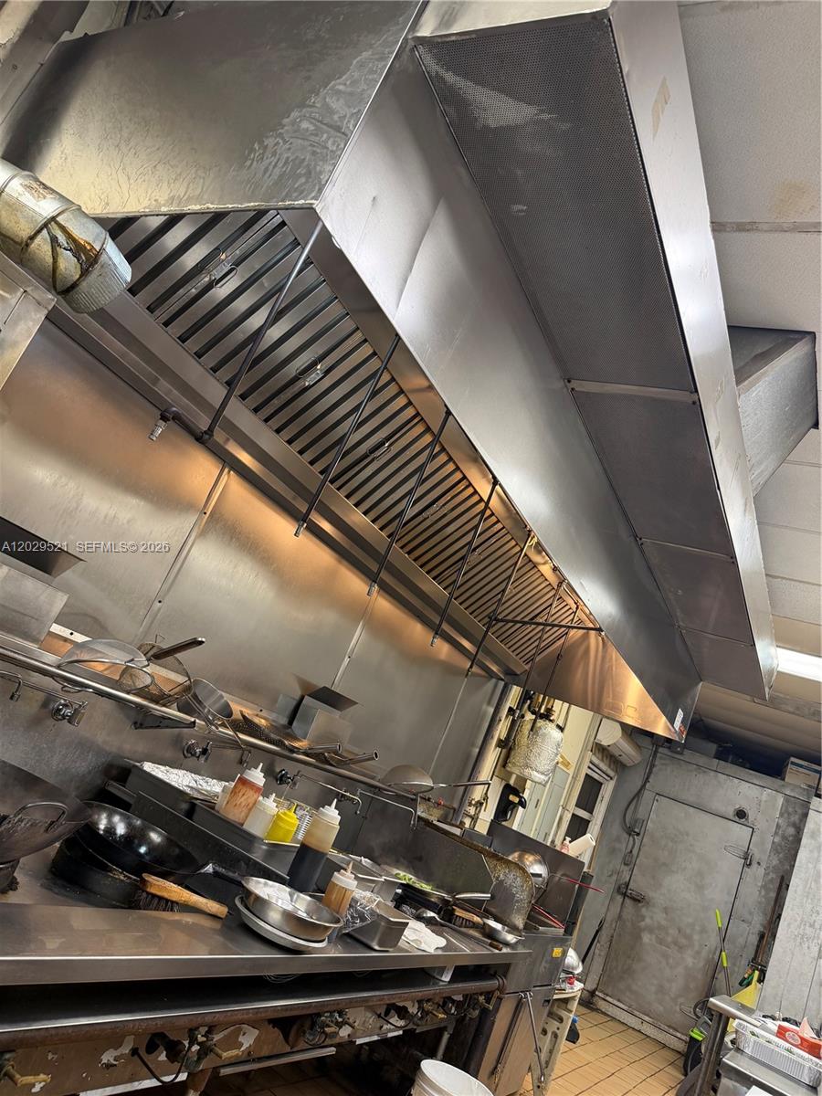 A commercial kitchen features stainless steel appliances, a large ventilation hood, and metal shelving — 7462 Royal Palm Blvd, Margate FL 33063, MARGATE, FL