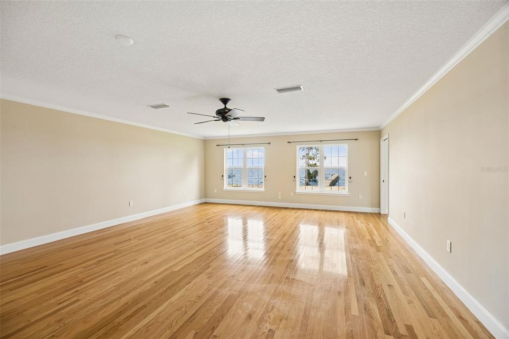 An empty room with light-colored walls, hardwood floors, a ceiling fan, and two windows — 102 SANDRA LANE, CRESCENT CITY, FL