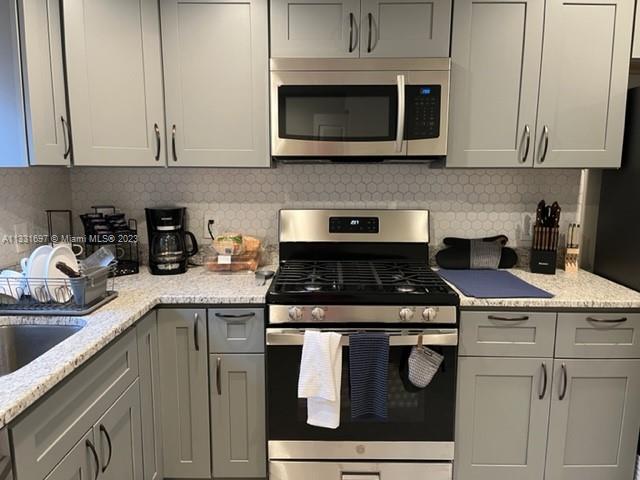 A kitchen features gray cabinets, stainless steel appliances, and a light-colored speckled countertop — 1247 S Newkirk, PA 19146, PA