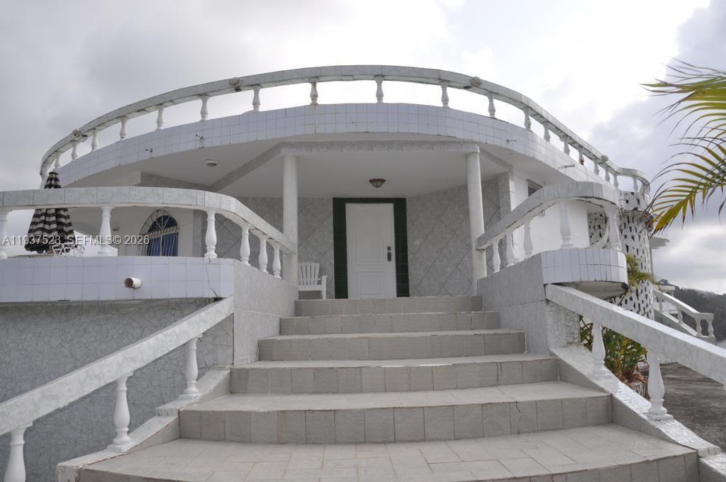 A white house exterior features a curved balcony, tiled stairs, and a central front door — N-A Portobello, Colon, P 3306, P