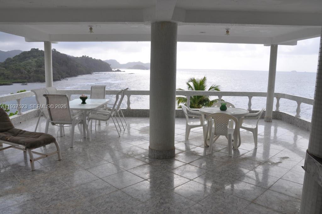 A covered outdoor patio features tile flooring, dining sets, and a scenic ocean view — N-A Portobello, Colon, P 3306, P