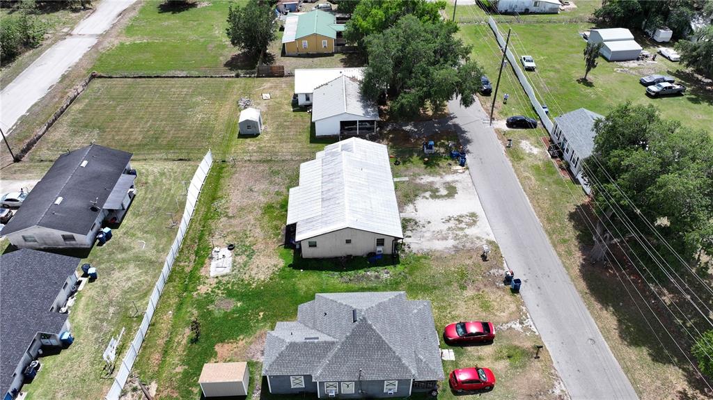 An aerial view shows several residential buildings, a long metal-roofed structure, and parked cars — 32 N PALMETTO AVENUE, FORT MEADE, FL
