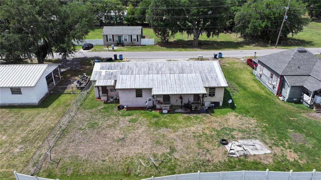 An aerial view shows a single-story duplex with a metal roof and a fenced backyard — 32 N PALMETTO AVENUE, FORT MEADE, FL