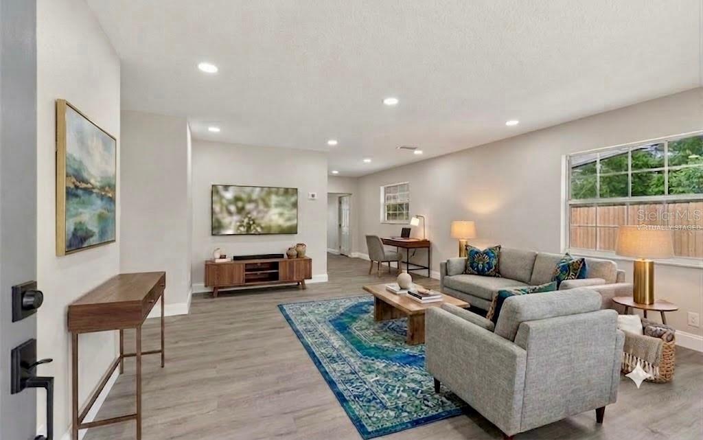 A living room features gray wood-look flooring, a blue area rug, and neutral-toned furniture — 6532 S WEST SHORE CIRCLE, TAMPA, FL