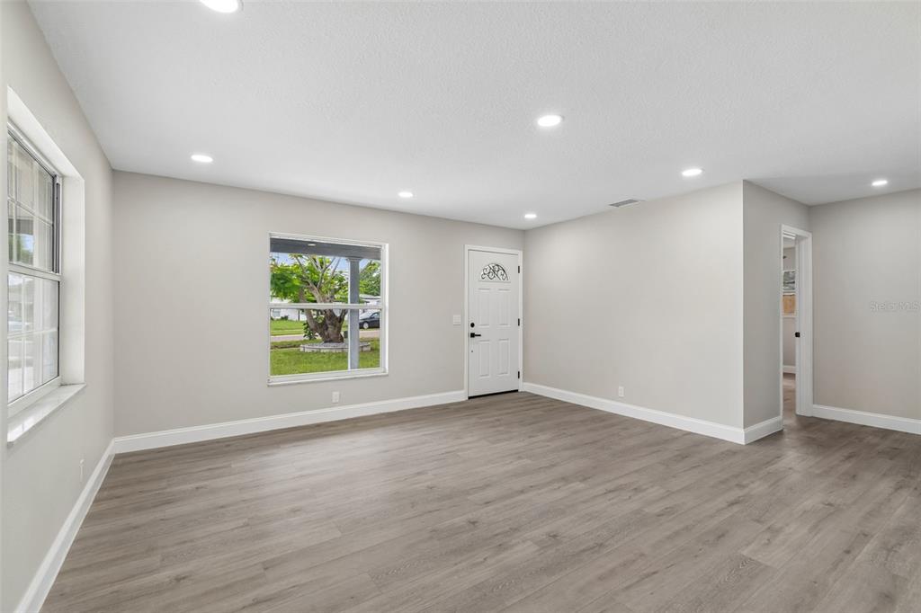 A bright living room features light gray walls, wood-look flooring, recessed lighting, and two windows — 6532 S WEST SHORE CIRCLE, TAMPA, FL